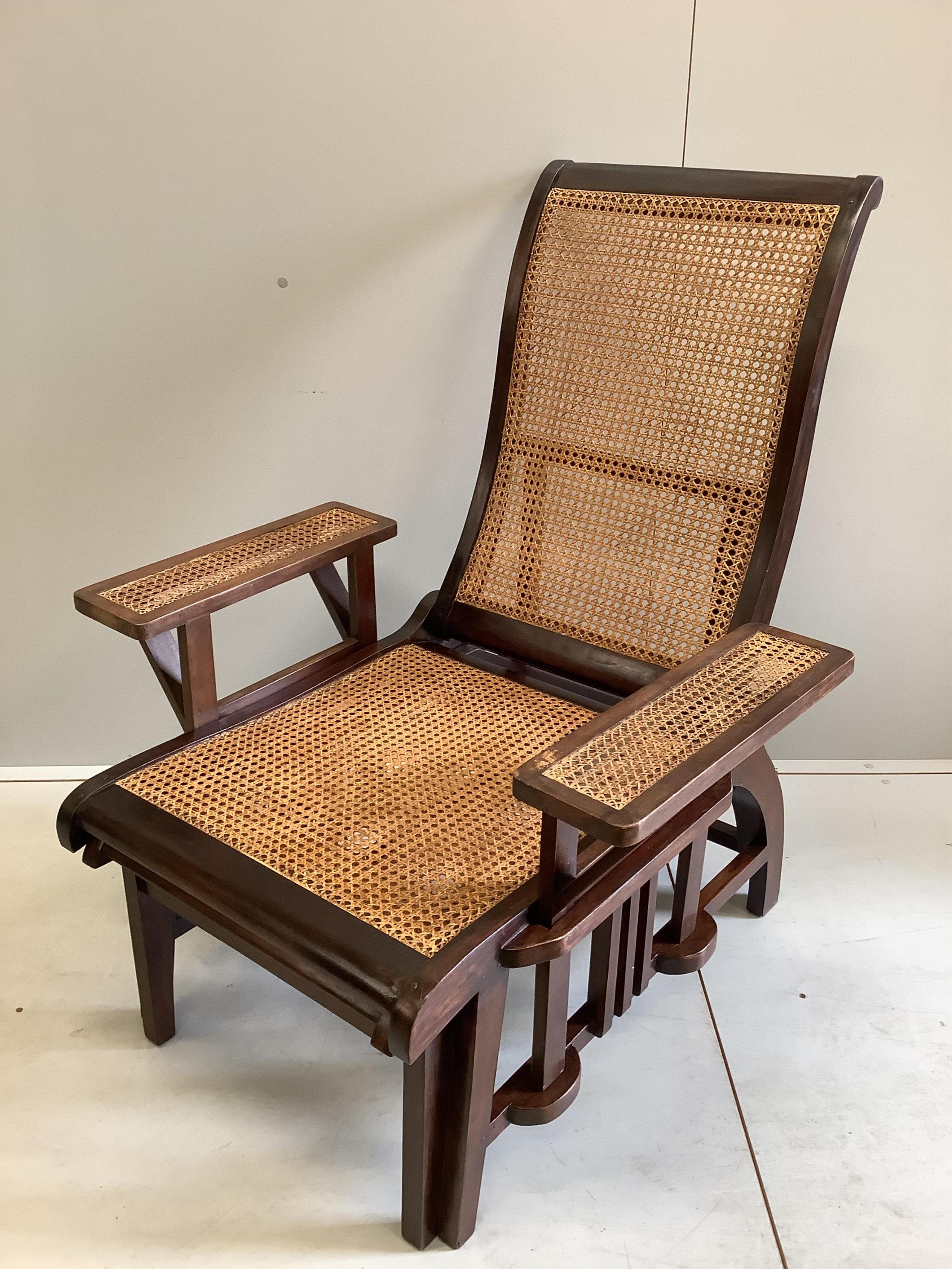 A pair of mid 20th century caned hardwood reclining garden chairs with integral sliding footrests and detachable armrests, width 85cm, depth 90cm, height 106cm. Condition - good